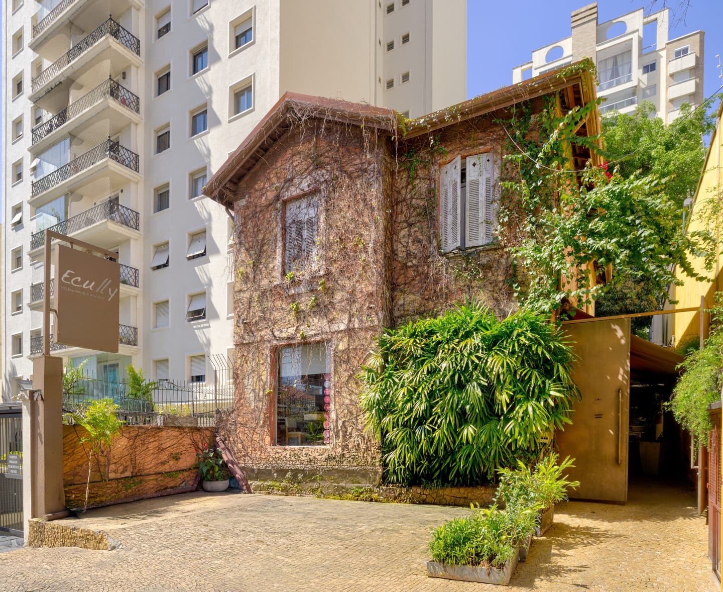 Fachada do restaurante Ecully, casa coberta de hera entre os prédios da Pompeia